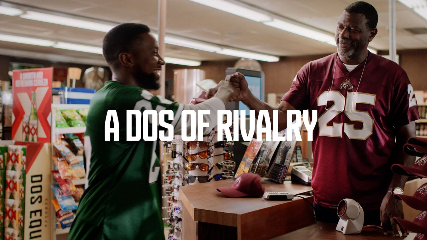 Two man rooting for rival teams fist bumping. Tag line that reads: A dos of rivalry.